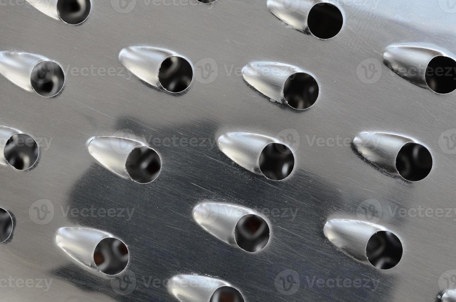 A fragment of a metal chrome grater close-up. Texture of blades for grinding food photo