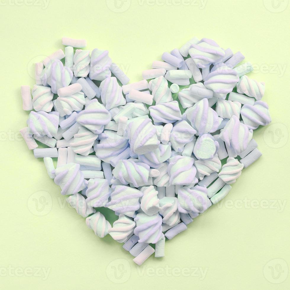 Colorful marshmallow laid out on lime and pink paper background. pastel creative textured heart photo