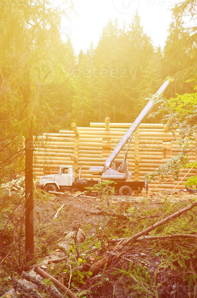 The process of building a wooden house from wooden beams of cylindrical shape. Crane in working condition photo