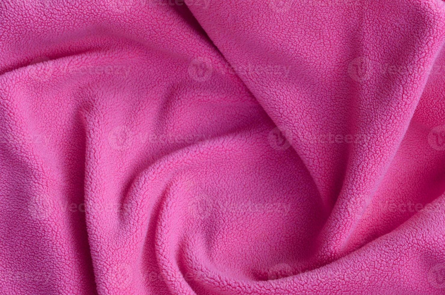 The blanket of furry pink fleece fabric. A background of light pink soft plush fleece material with a lot of relief folds photo
