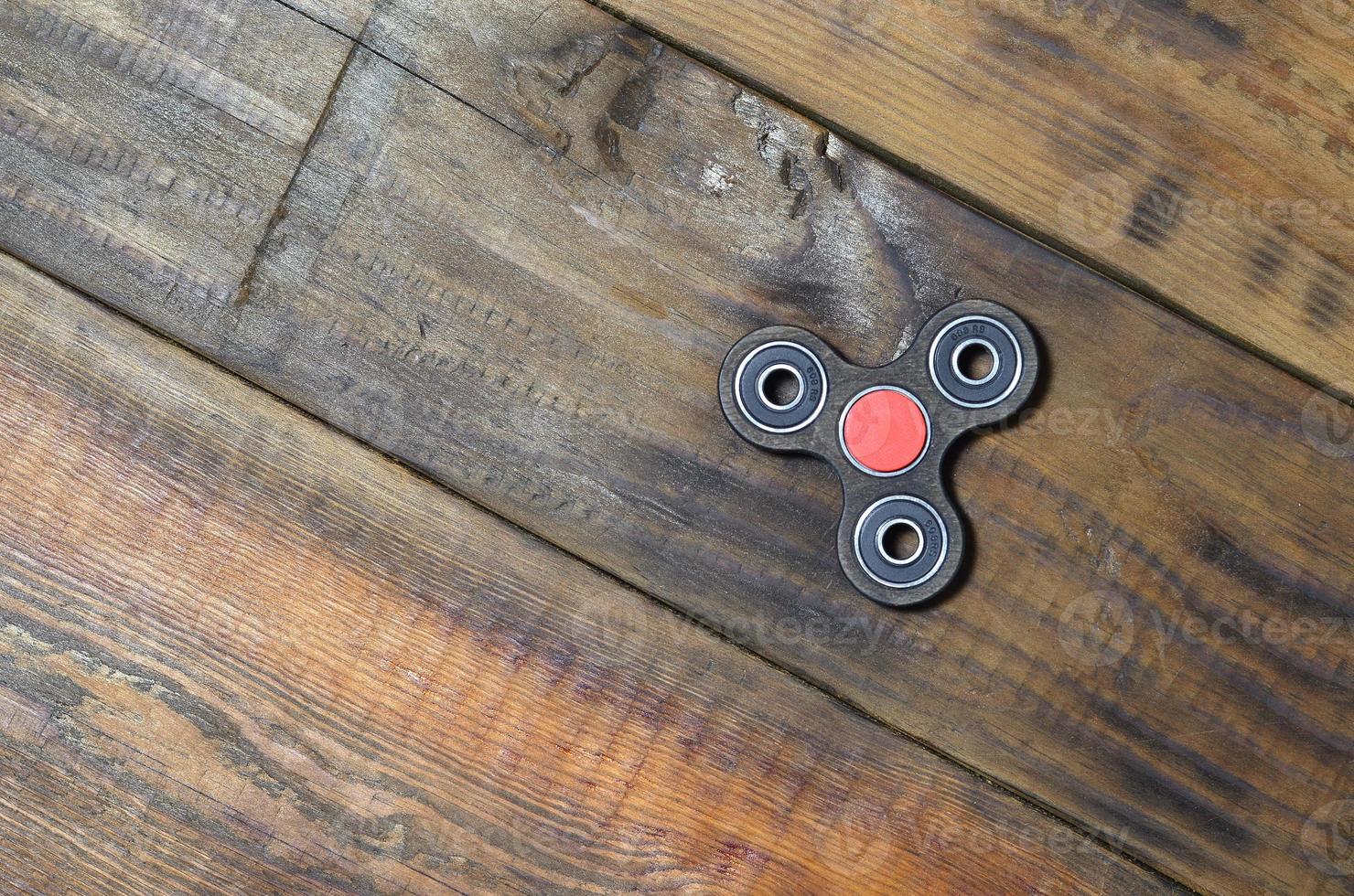 A rare handmade wooden fidget spinner lies on a brown wooden background surface. Trendy stress relieving toy photo