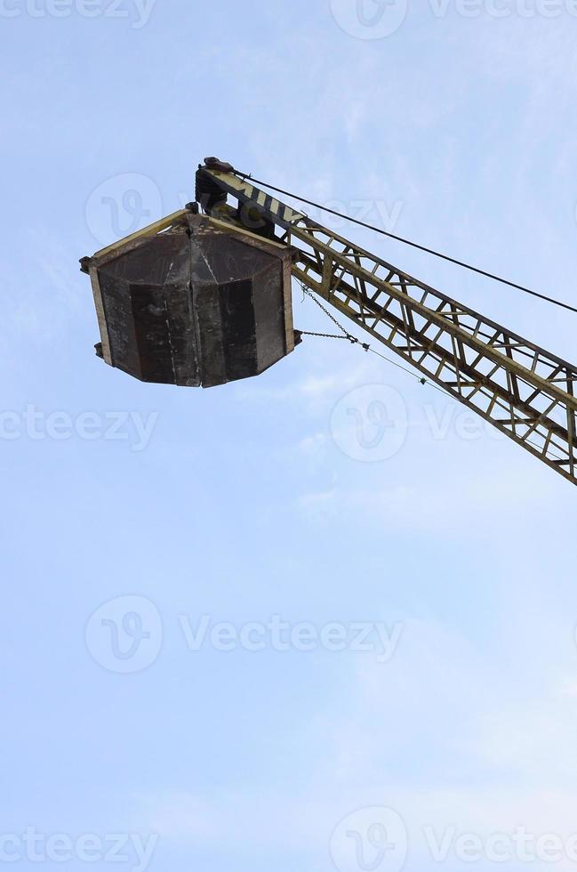 Old yellow mechanical clamshell grab on blue sky background photo