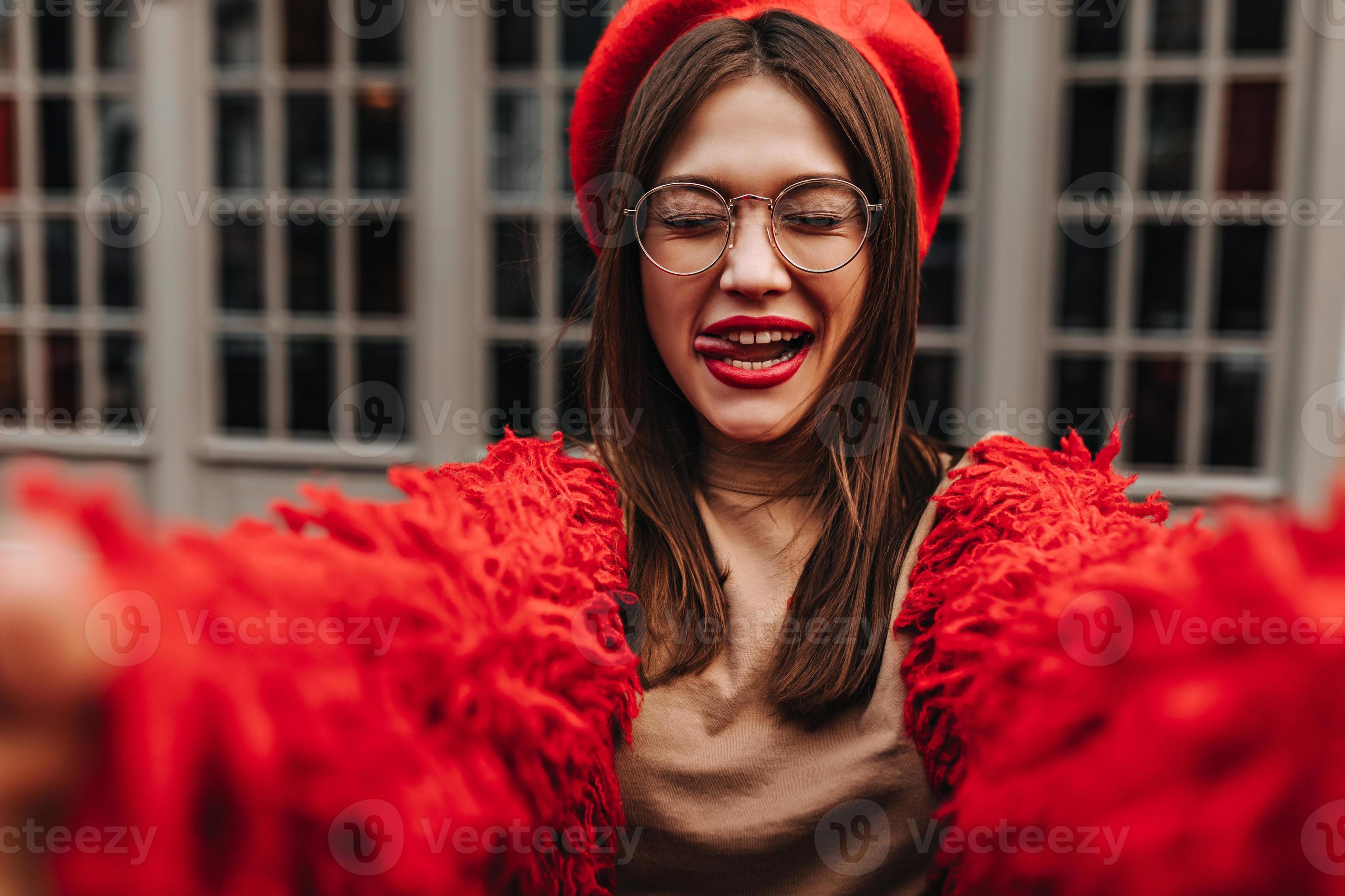 Perky girl with red lipstick shows tongue. Lady in red outfit and