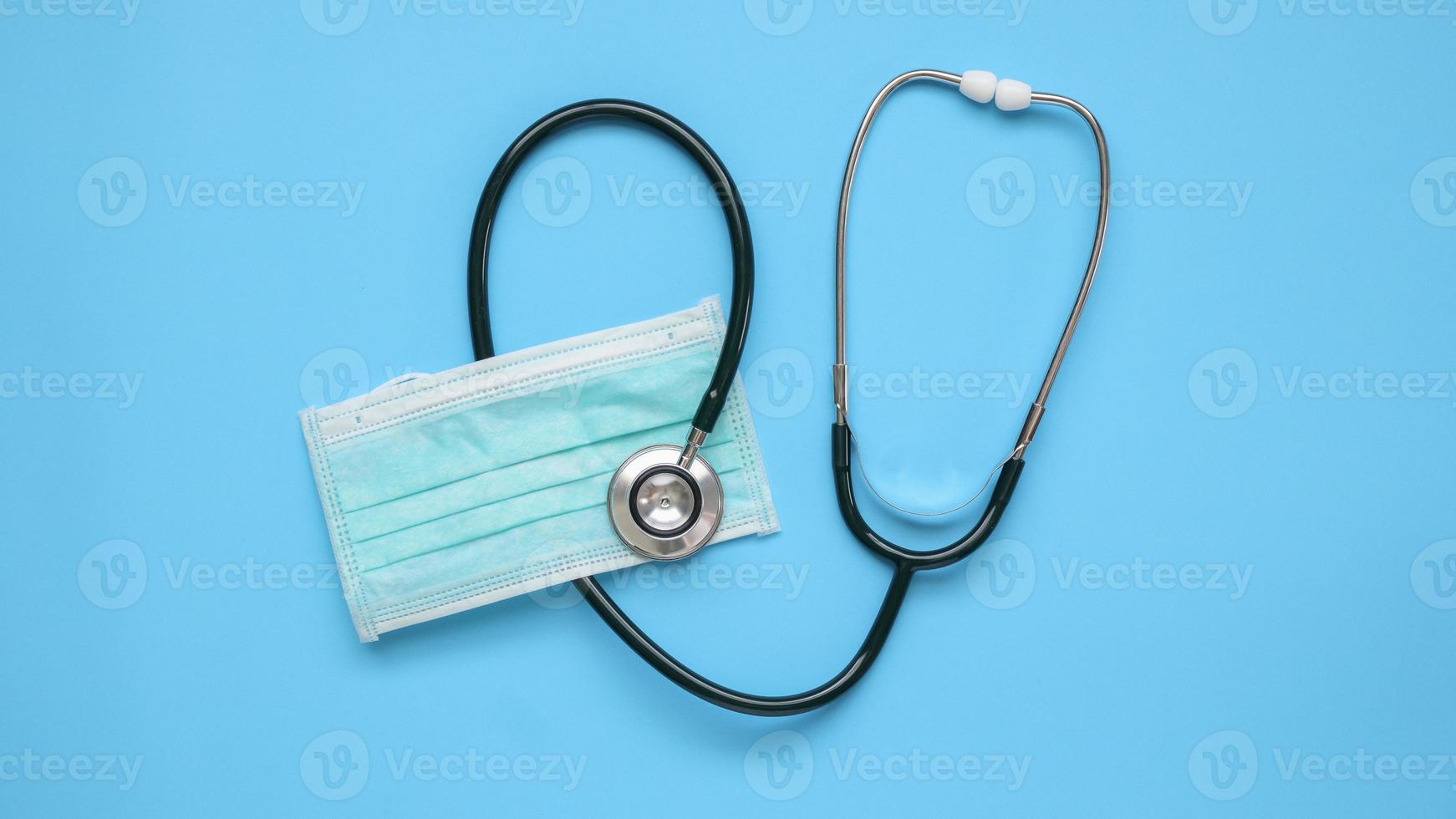 Stethoscope medical equipment with surgical face mask on blue background covid-19 Coronavirus prevention healthcare concept photo