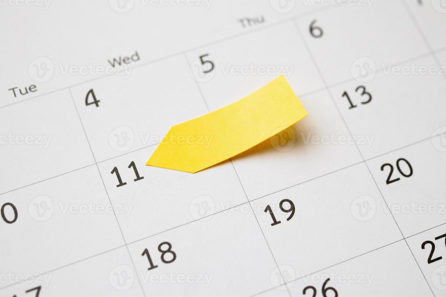 Blank yellow sticky adhesive post note paper planner with space on calendar page background for business planning appointment meeting concept photo