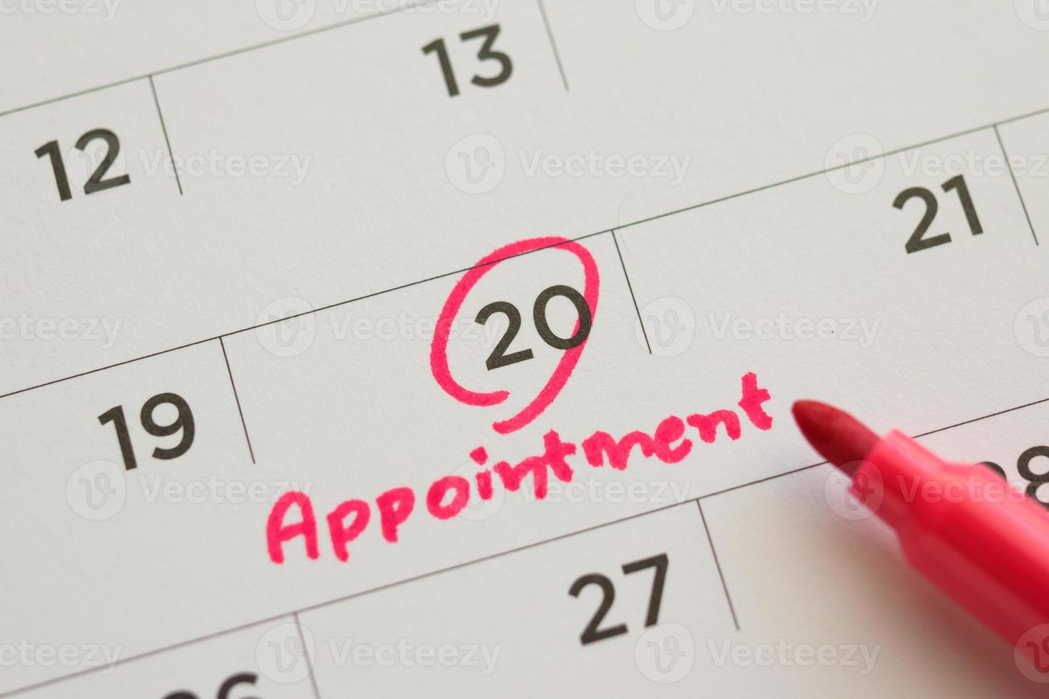 Red color marker pen pointing at important appointment schedule on white calendar page date close up photo