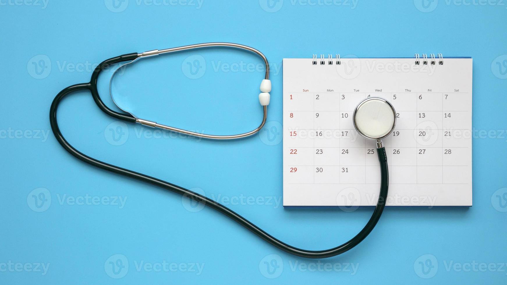 Stethoscope with calendar page date on blue background doctor appointment medical concept photo