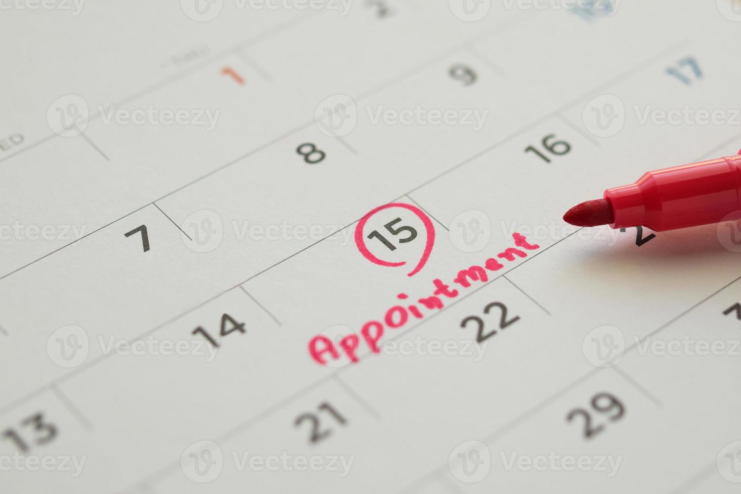 Red color marker pen pointing at important appointment schedule on white calendar page date close up photo