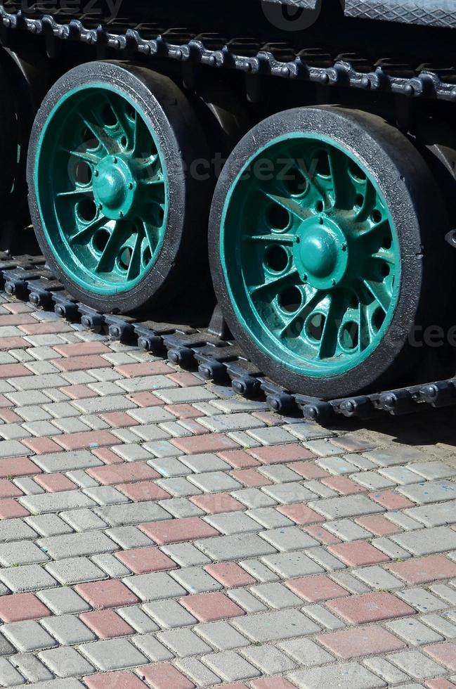 A military vehicle on caterpillar tracks stands on a square of paving stones. Photo of green caterpillars with metal wheels that rotate them