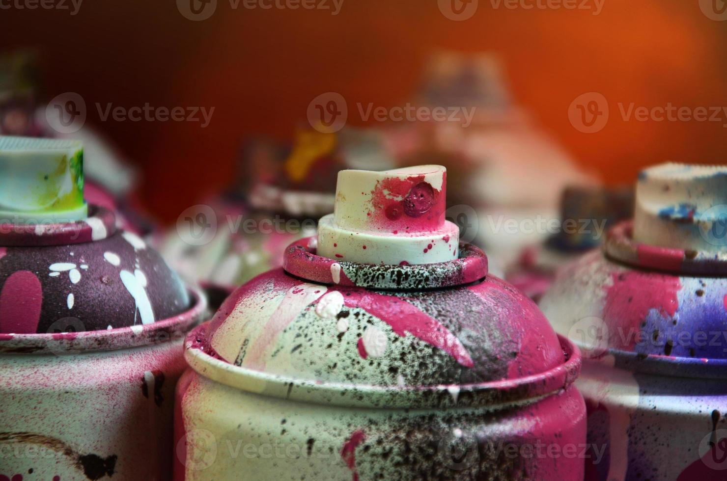 Still life with a large number of used colorful spray cans of aerosol paint lying on the treated wooden surface in the artist's graffiti workshop. Dirty and stained cans for spray art photo