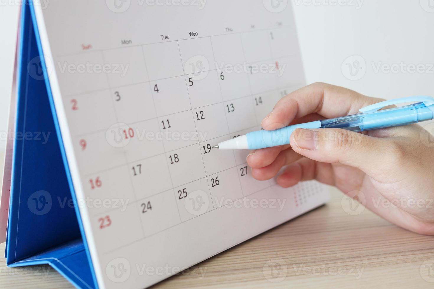 Hand with pen writing on calendar date photo