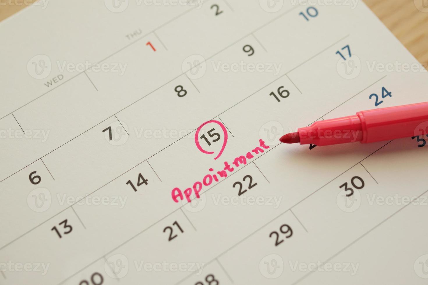 Red color marker pen pointing at important appointment schedule on white calendar page date close up photo