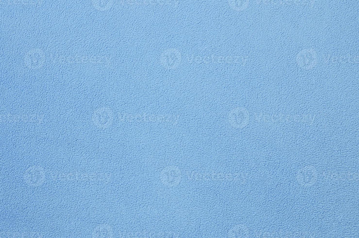 The blanket of furry blue fleece fabric. A background texture of light blue soft plush fleece material photo