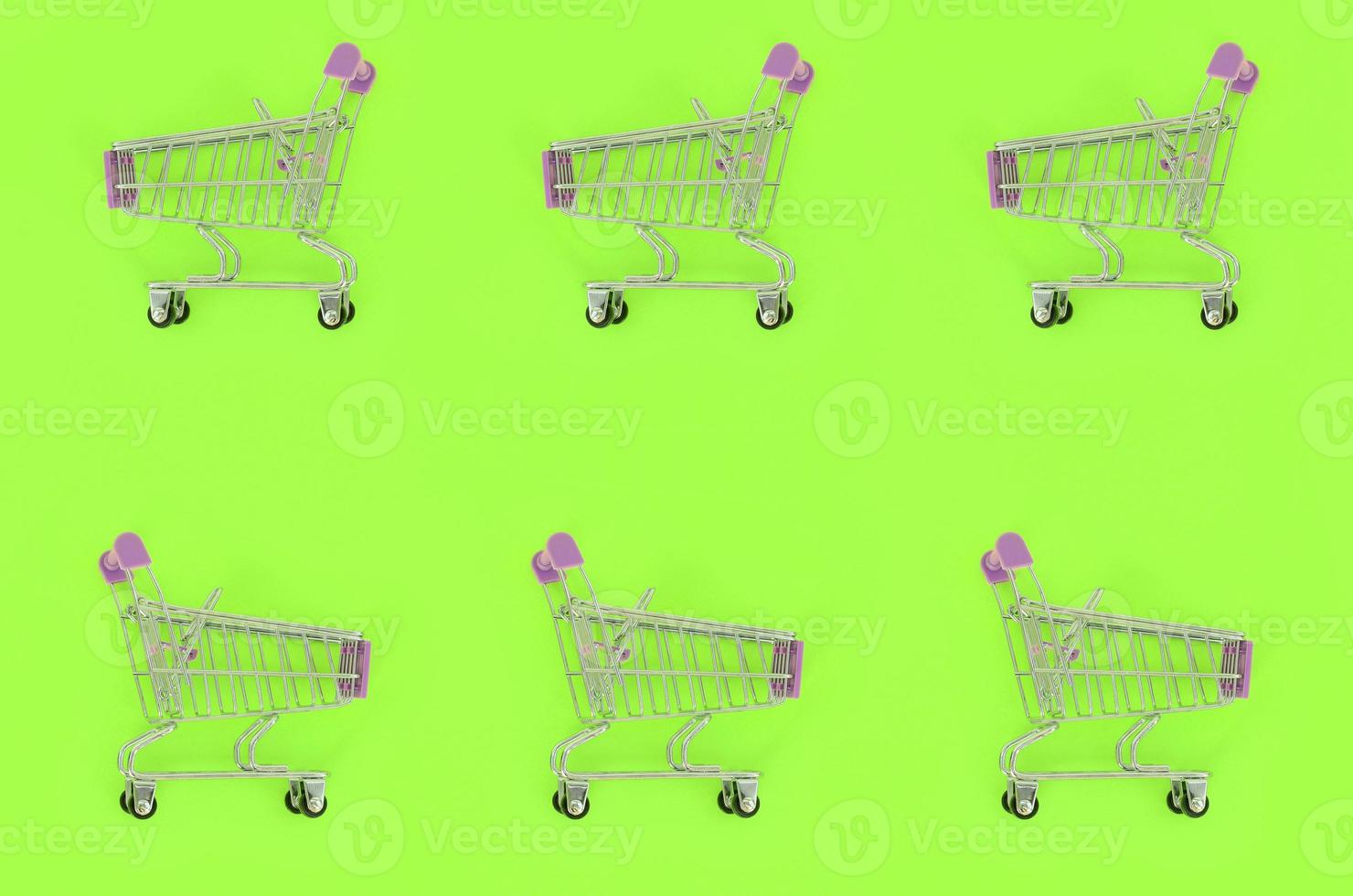 Shopping addiction, shopping lover or shopaholic concept. Many small empty shopping carts perform a pattern on a pastel colored paper background. Flat lay composition, top view photo