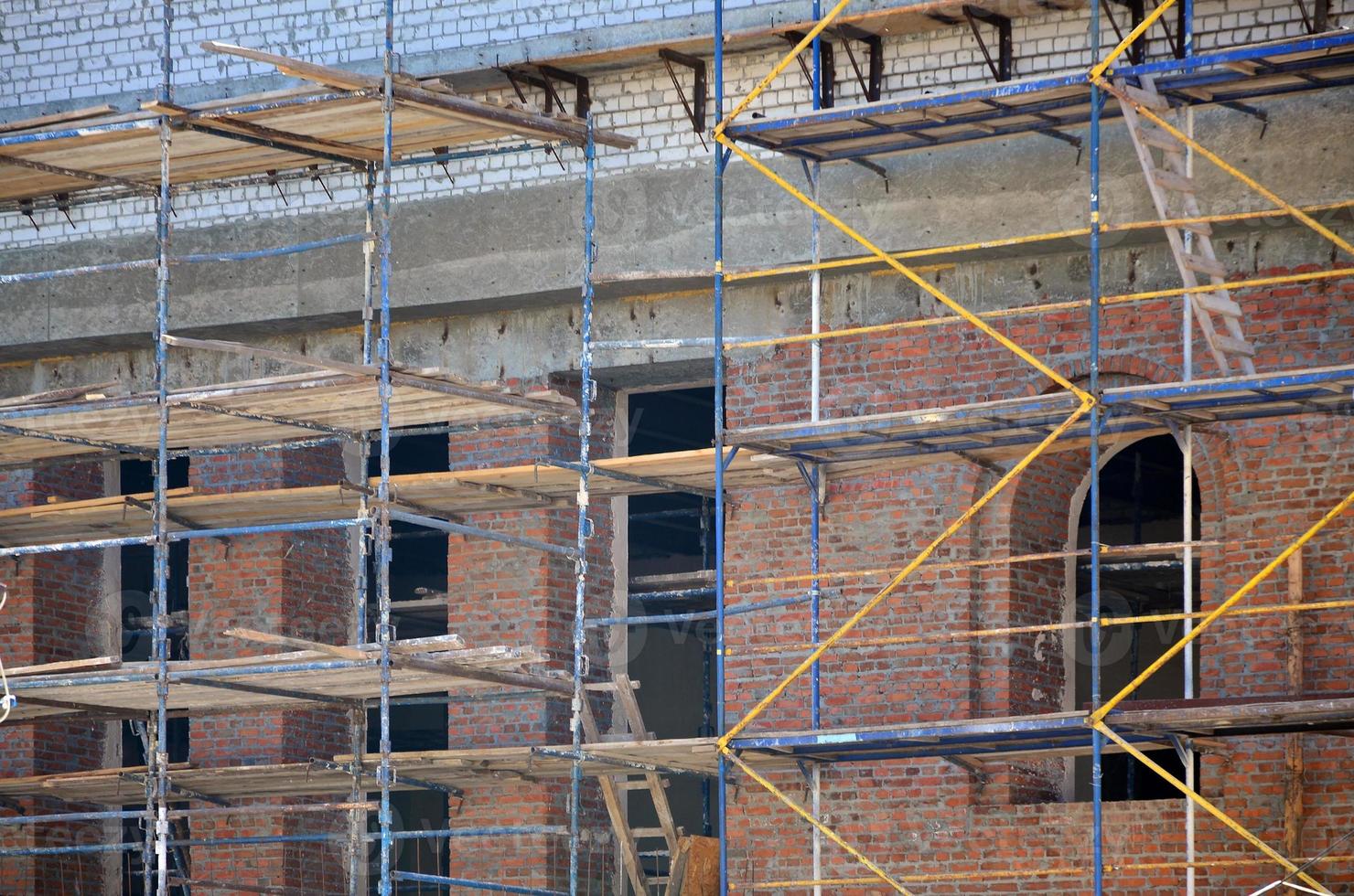 Scaffolds installed near the multi-storey brick building under construction photo