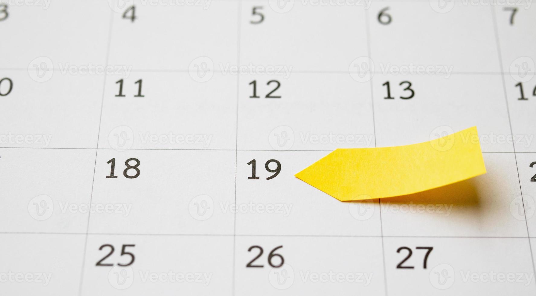 Blank yellow sticky adhesive post note paper planner with space on calendar page background for business planning appointment meeting concept photo