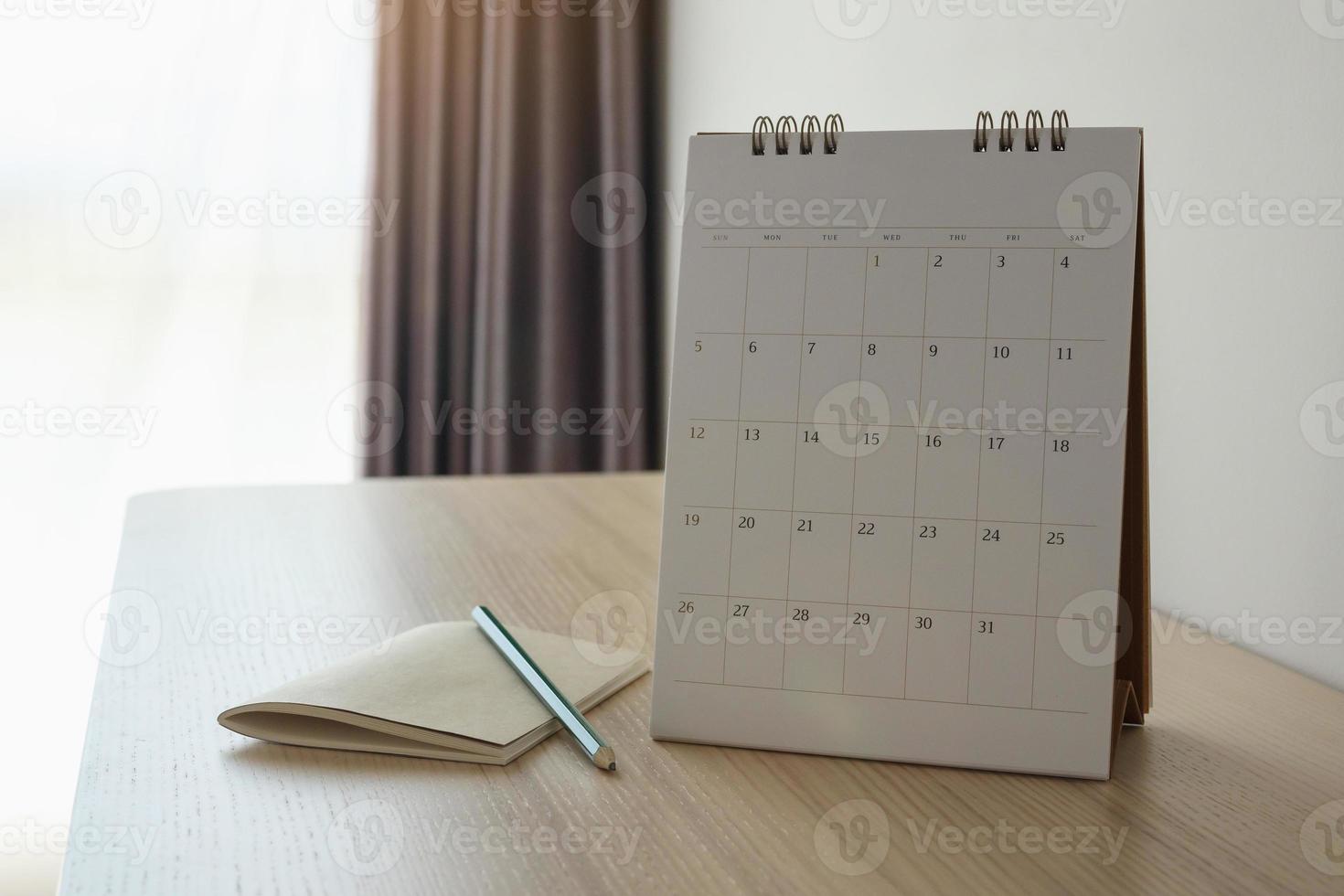 calendar page close up on wood table background with pencil and notebook business planning appointment meeting concept photo