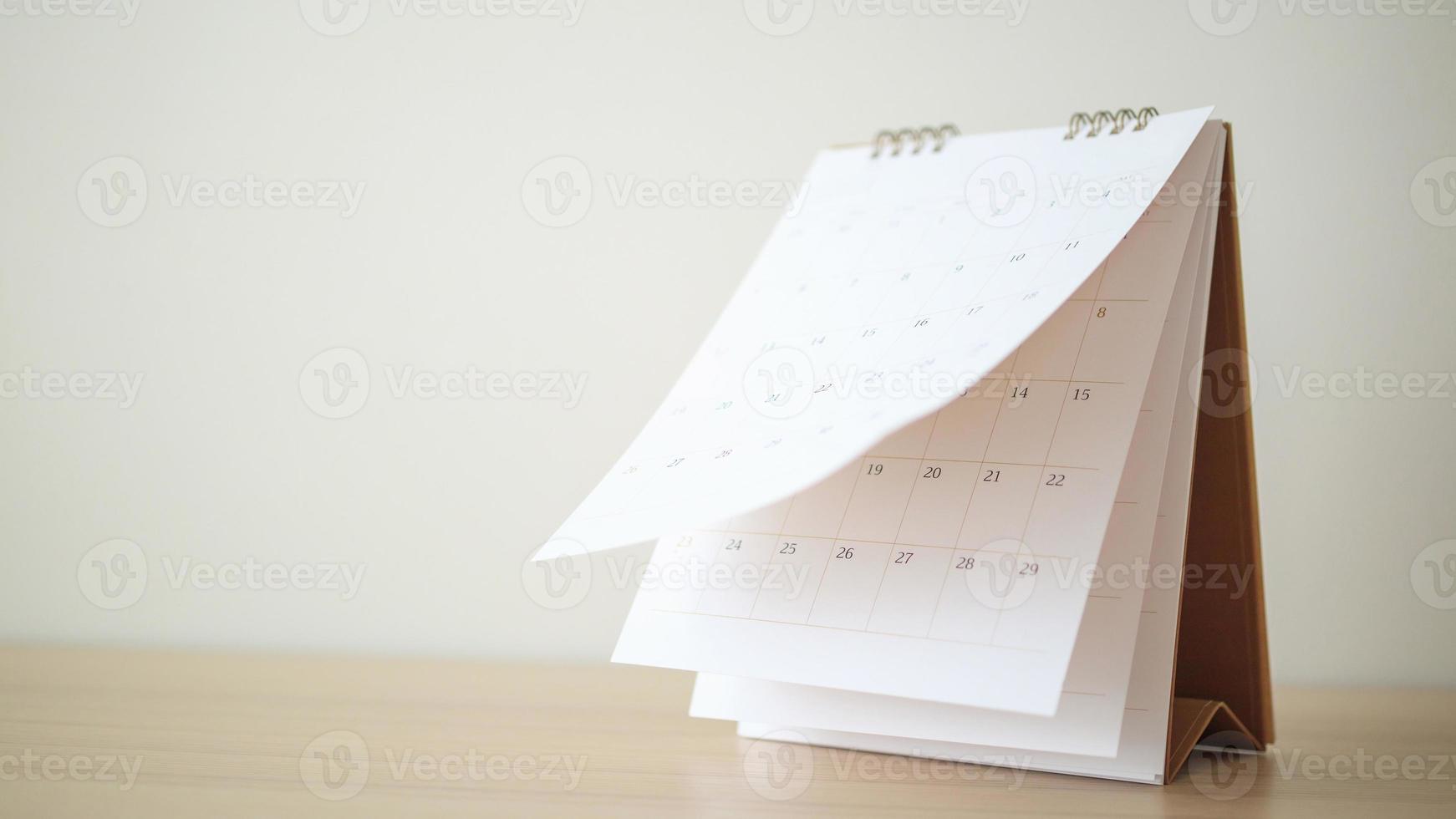 Calendar page flipping sheet on wood table background business schedule planning appointment meeting concept photo