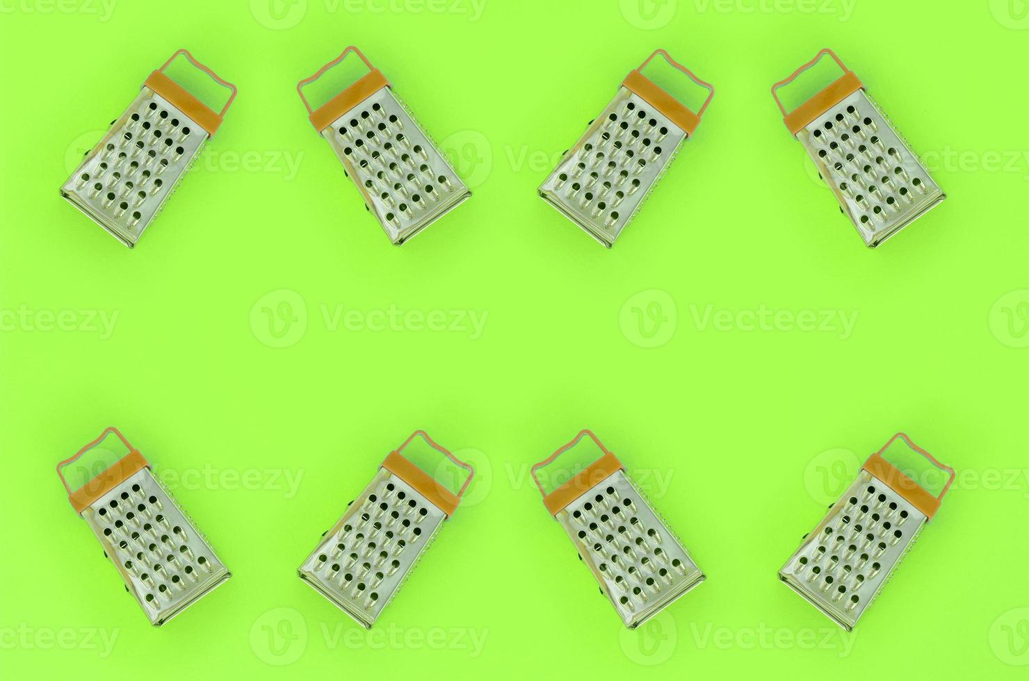 Small stainless steel graters lies on a pastel colored paper. Kitchen accessories. Tools for cooking. Flat lay top view photo