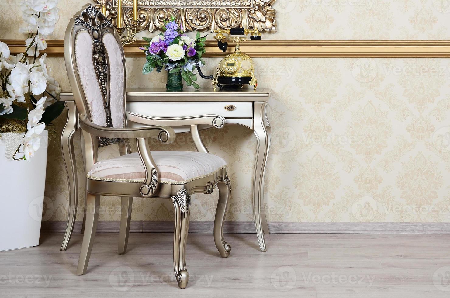 A fragment of a retro interior with a chair and a desk on which is located a telephone and a vase of flowers photo