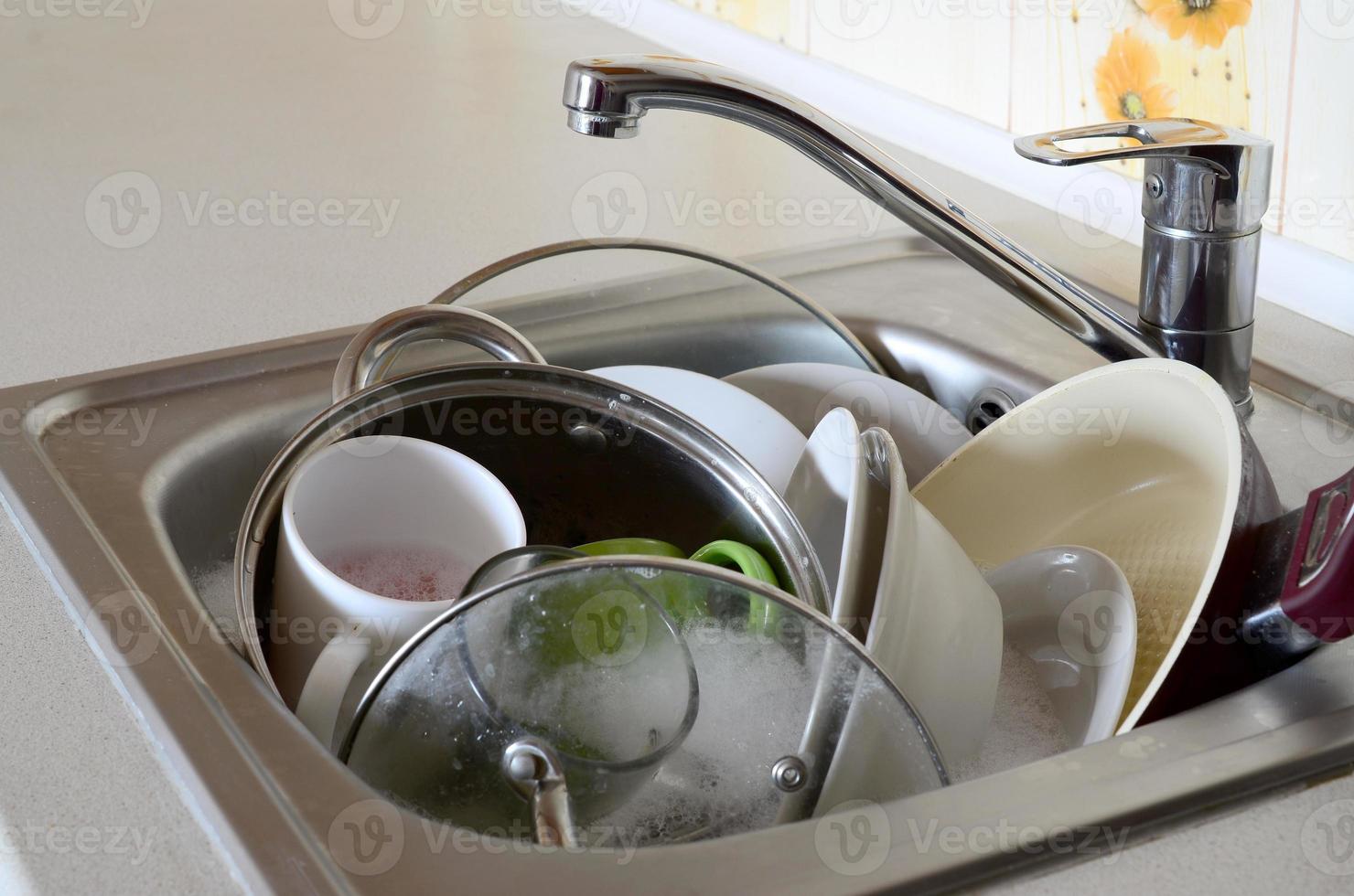 platos sucios y electrodomésticos de cocina sin lavar llenaron el fregadero de la cocina foto