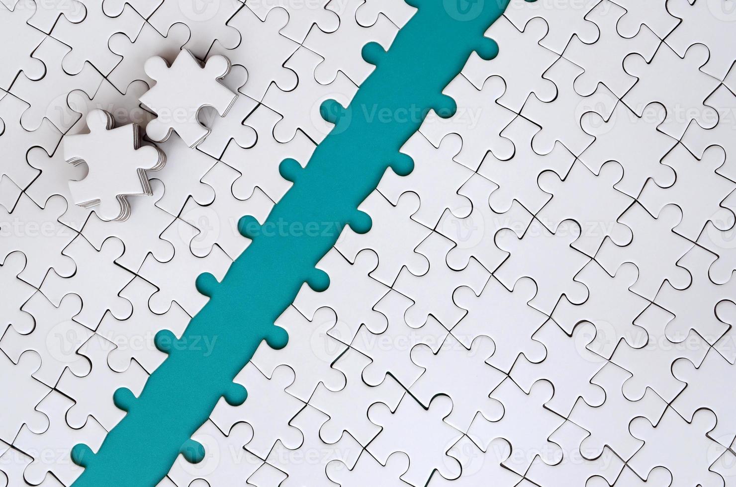 The blue path is laid on the platform of a white folded jigsaw puzzle. The missing elements of the puzzle are stacked nearby. Texture image with space for text photo