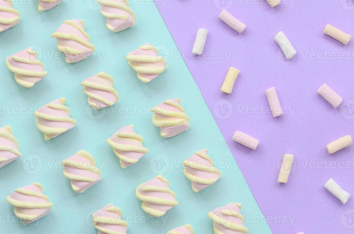 Colorful marshmallow laid out on violet and blue paper background. pastel creative textured pattern. minimal photo