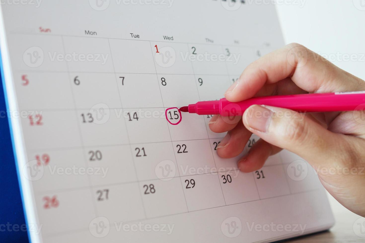 Hand with pen mark at 15th on calendar date photo