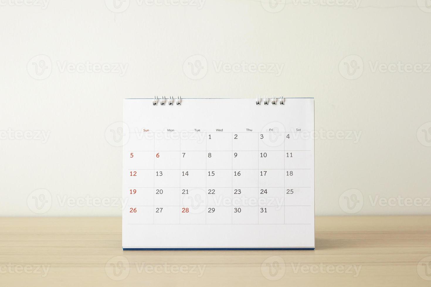 Calendar page close up on wood table with white wall background business planning appointment meeting concept photo