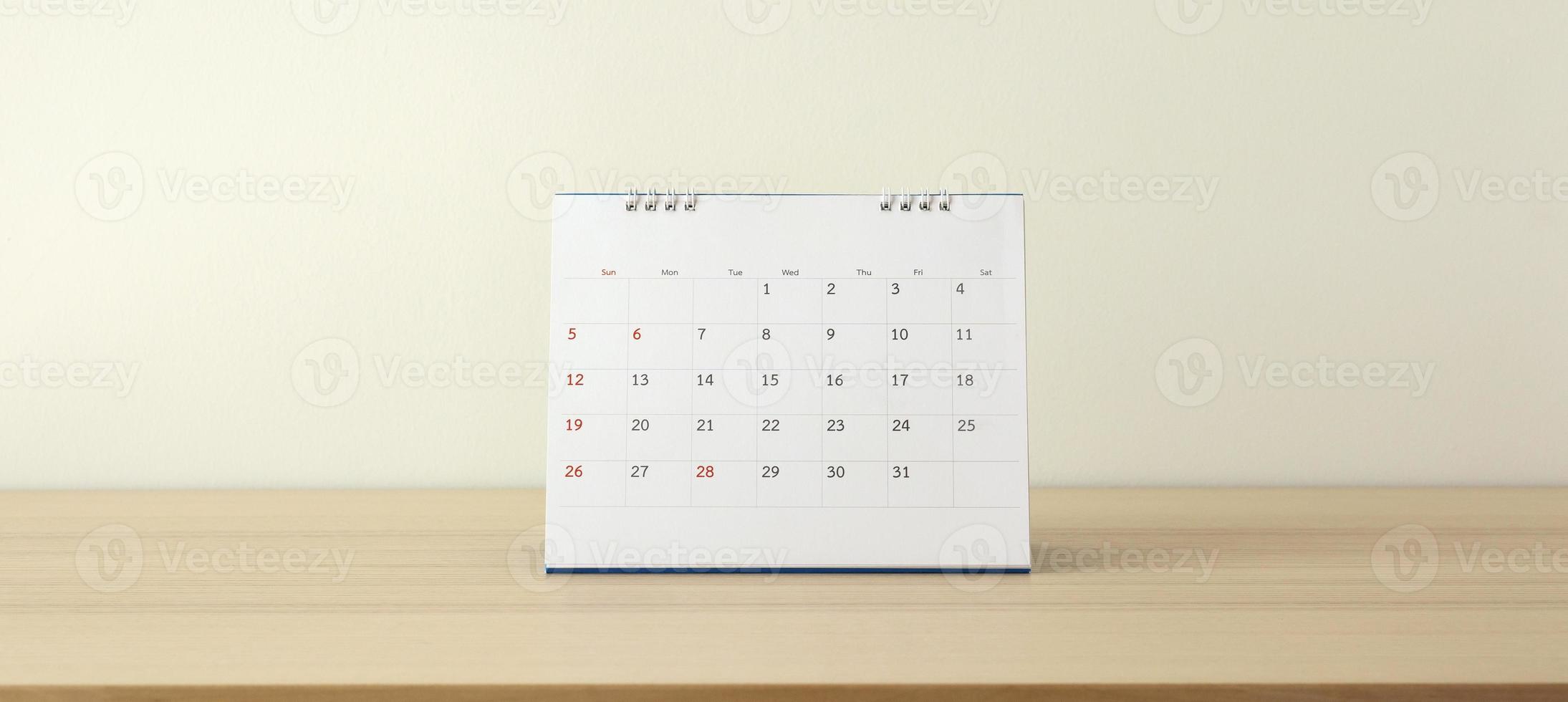 Calendar page close up on wood table with white wall background business planning appointment meeting concept photo