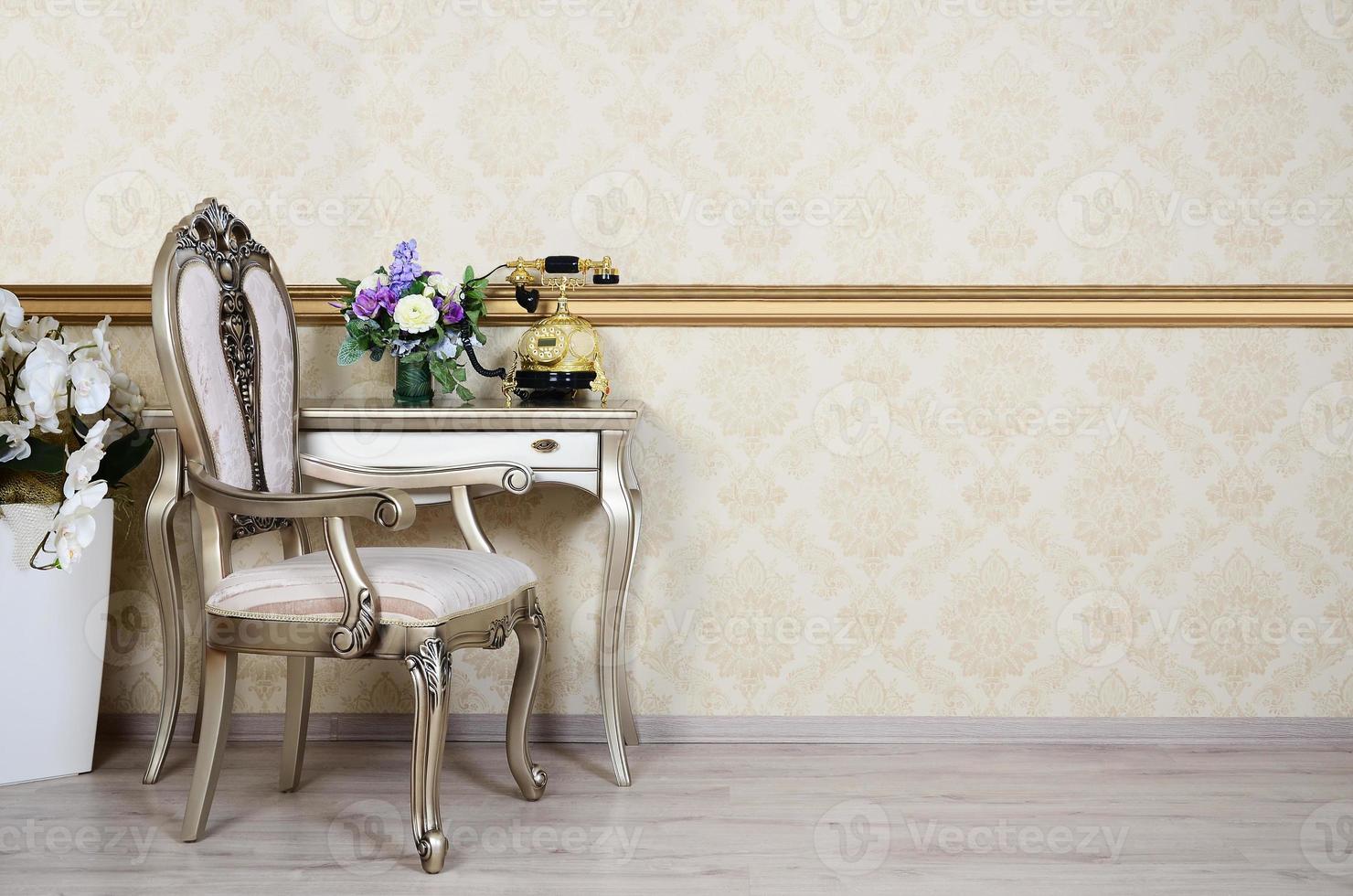 A fragment of a retro interior with a chair and a desk on which is located a telephone and a vase of flowers photo