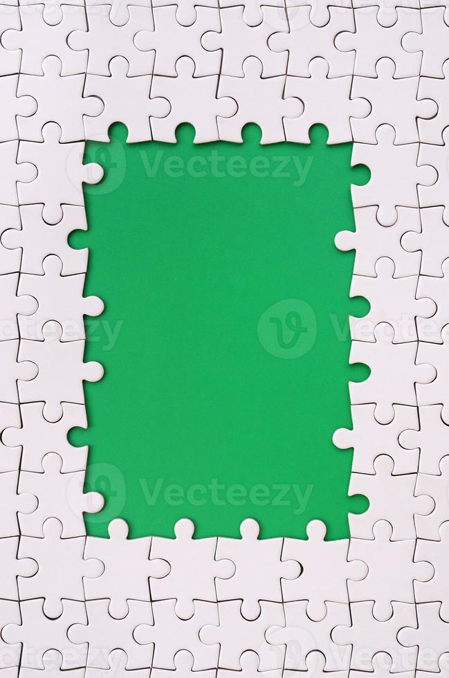 Framing in the form of a rectangle, made of a white jigsaw puzzle around the green space photo
