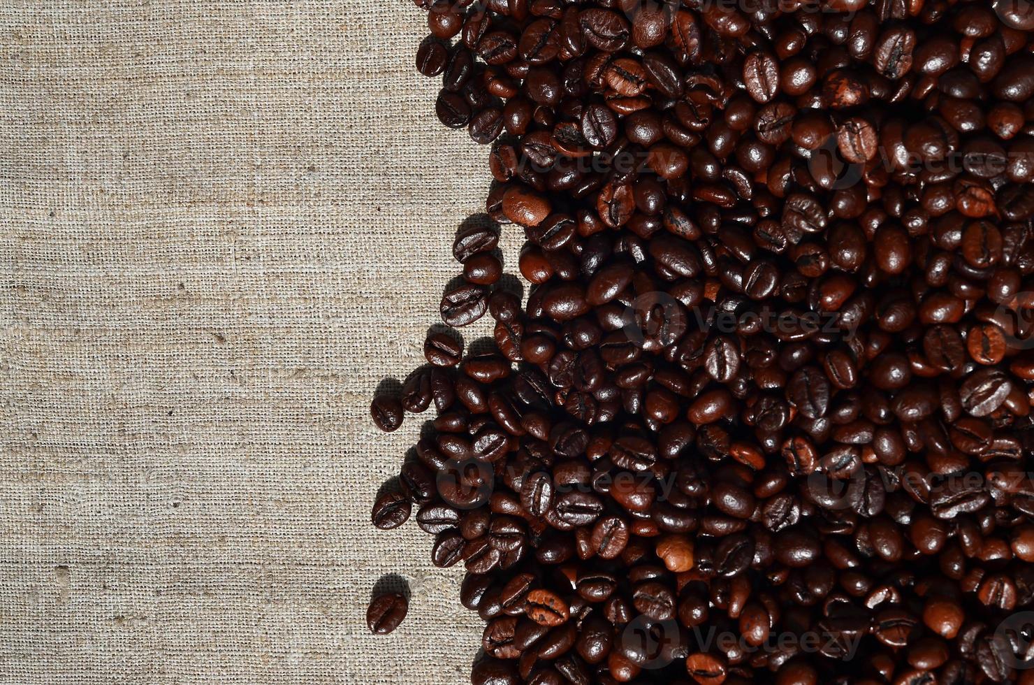Texture of a gray canvas made of old and coarse burlap with coffee beans on it photo