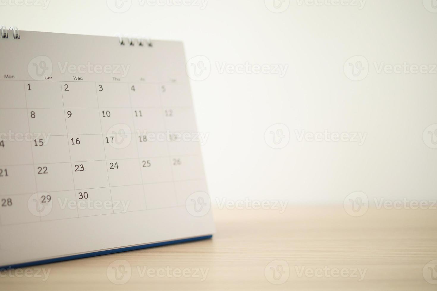 Calendar page close up on wood table with white wall background photo