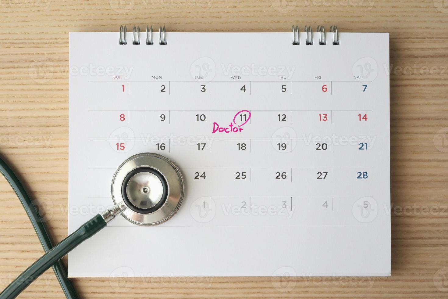 Stethoscope with calendar page date on wood table background doctor appointment medical concept photo