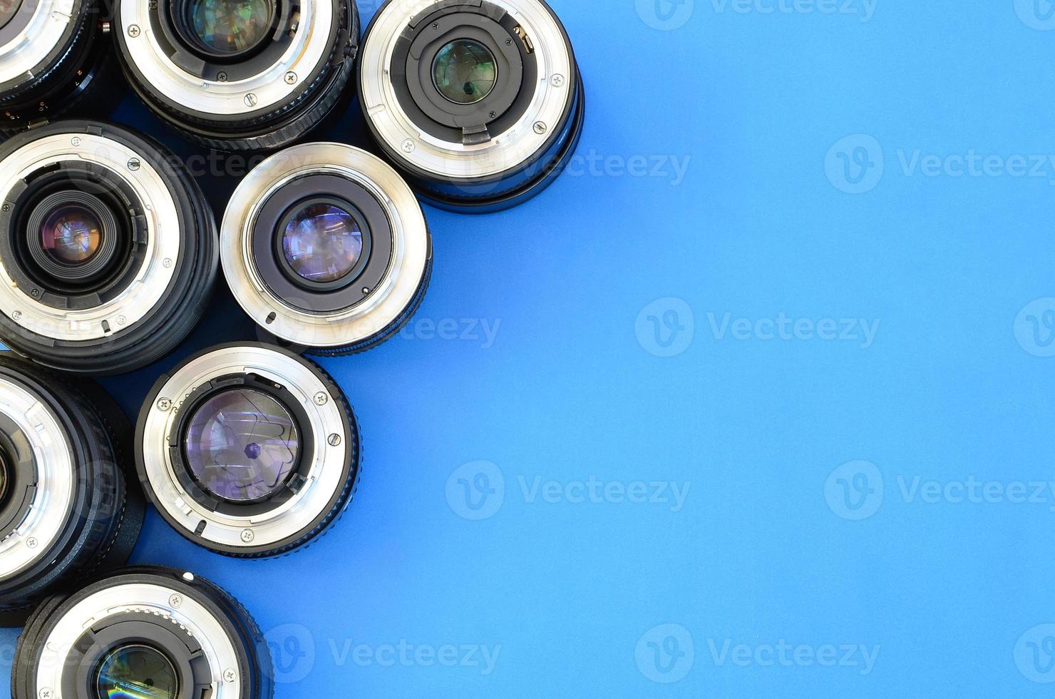 Several photographic lenses lie on a bright blue background. Space for text photo