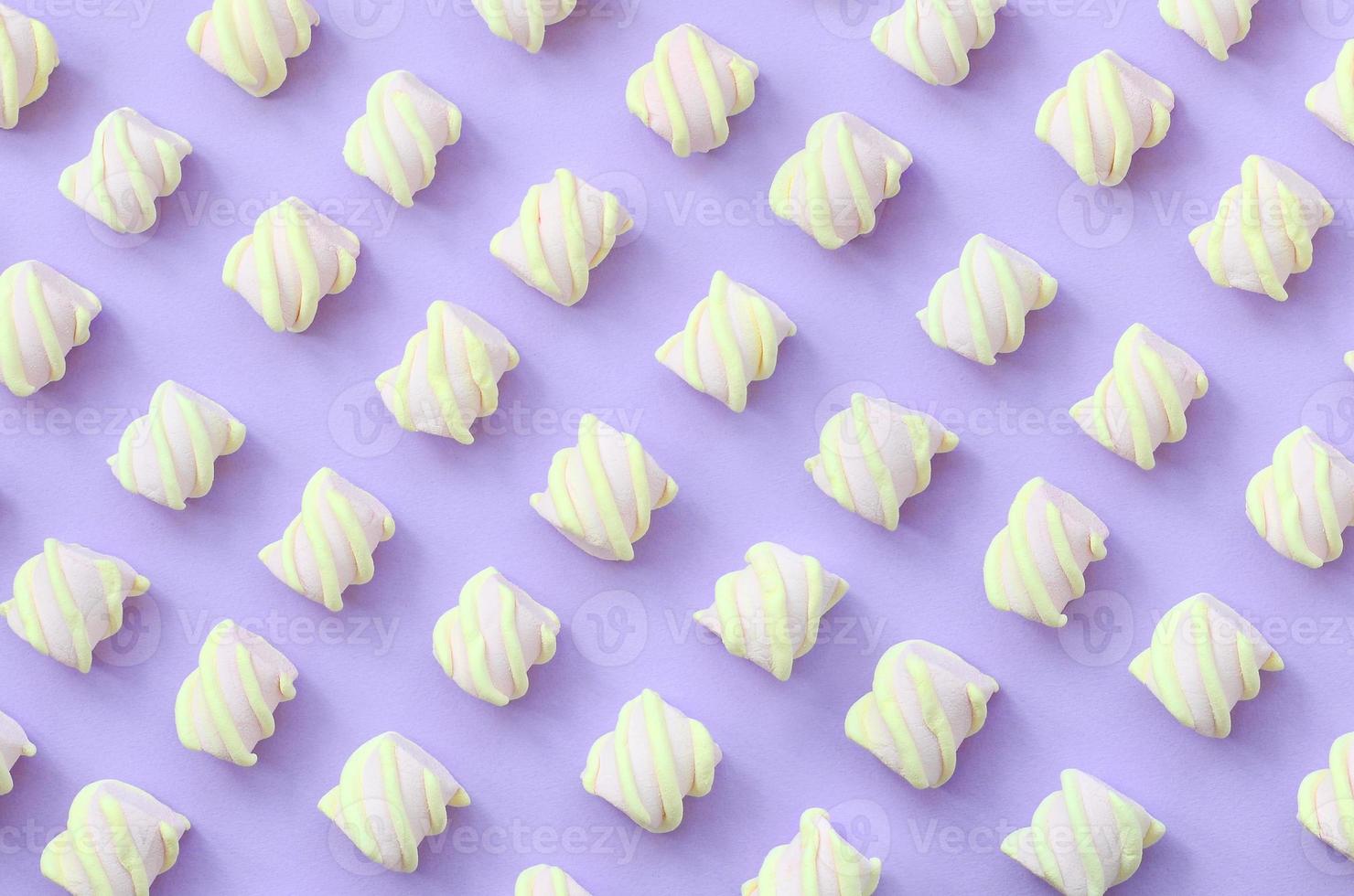 Colorful marshmallow laid out on violet paper background. pastel creative textured pattern. minimal photo