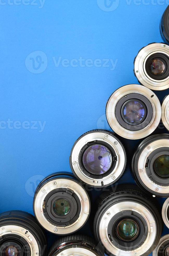 Several photographic lenses lie on a bright blue background. Space for text photo