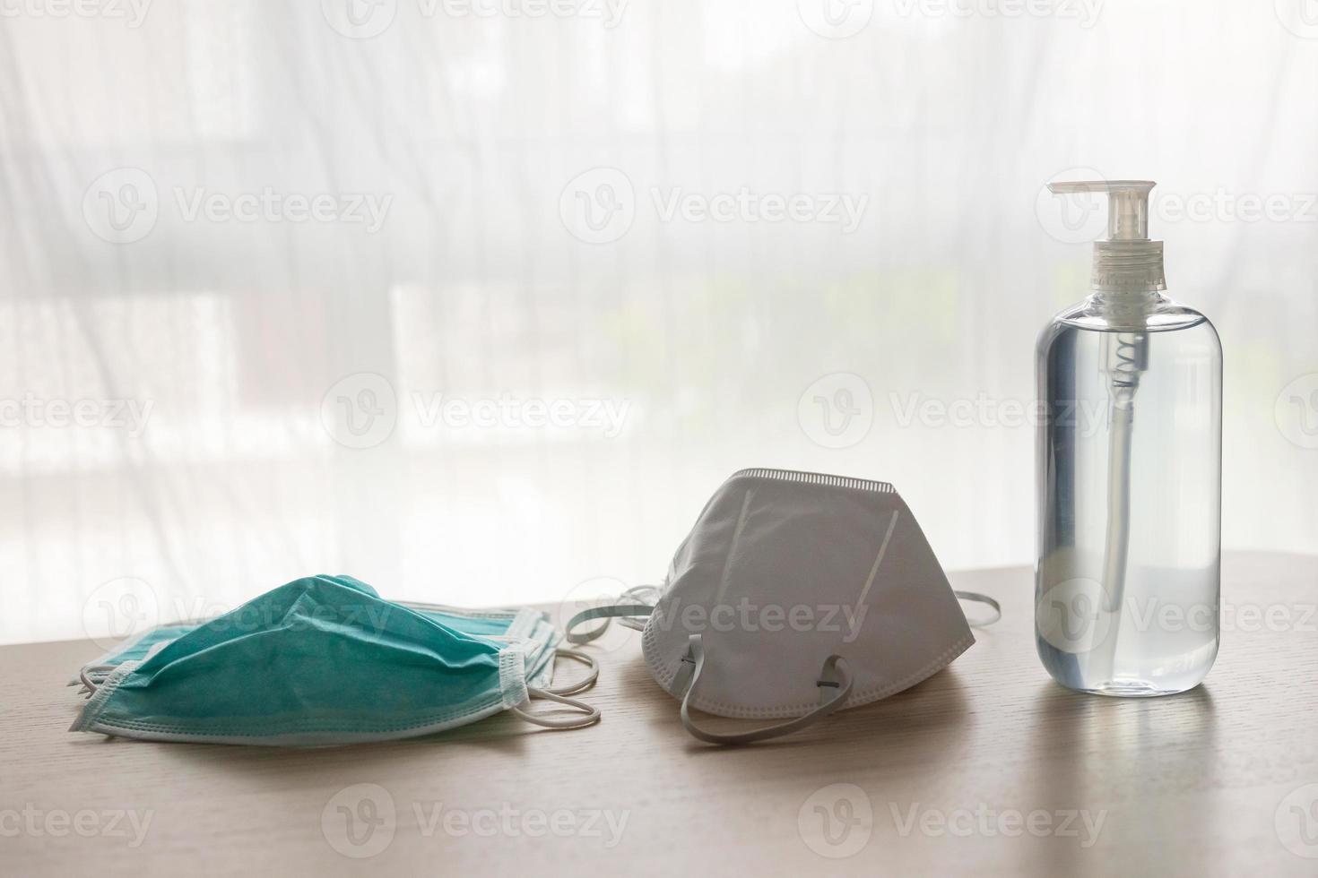 mascarilla médica con gel desinfectante de alcohol lavado a mano en mesa de madera para el concepto de prevención del coronavirus covid-19 foto
