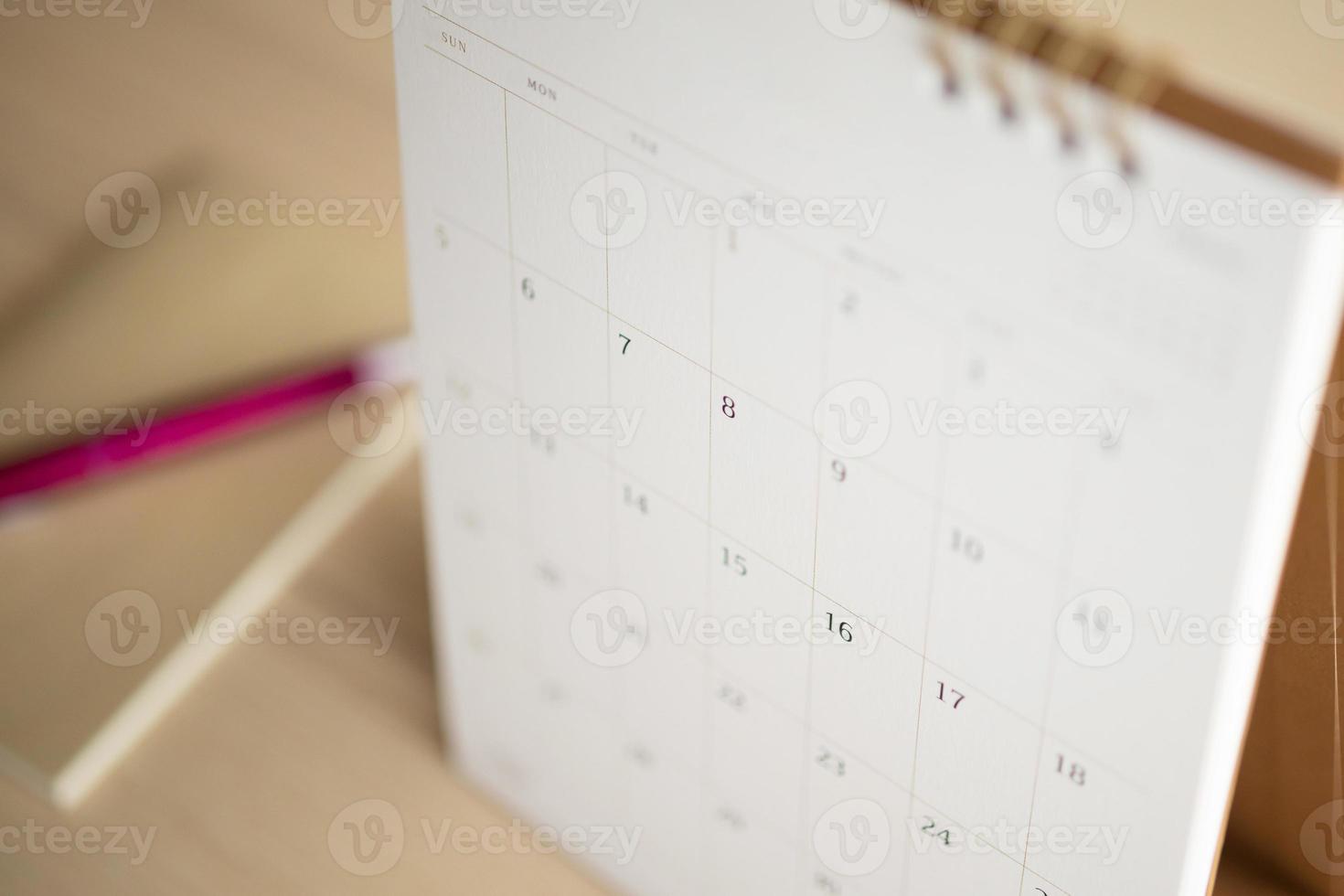 página del calendario de cerca en el fondo de la mesa de madera con bolígrafo y cuaderno concepto de reunión de cita de planificación empresarial foto