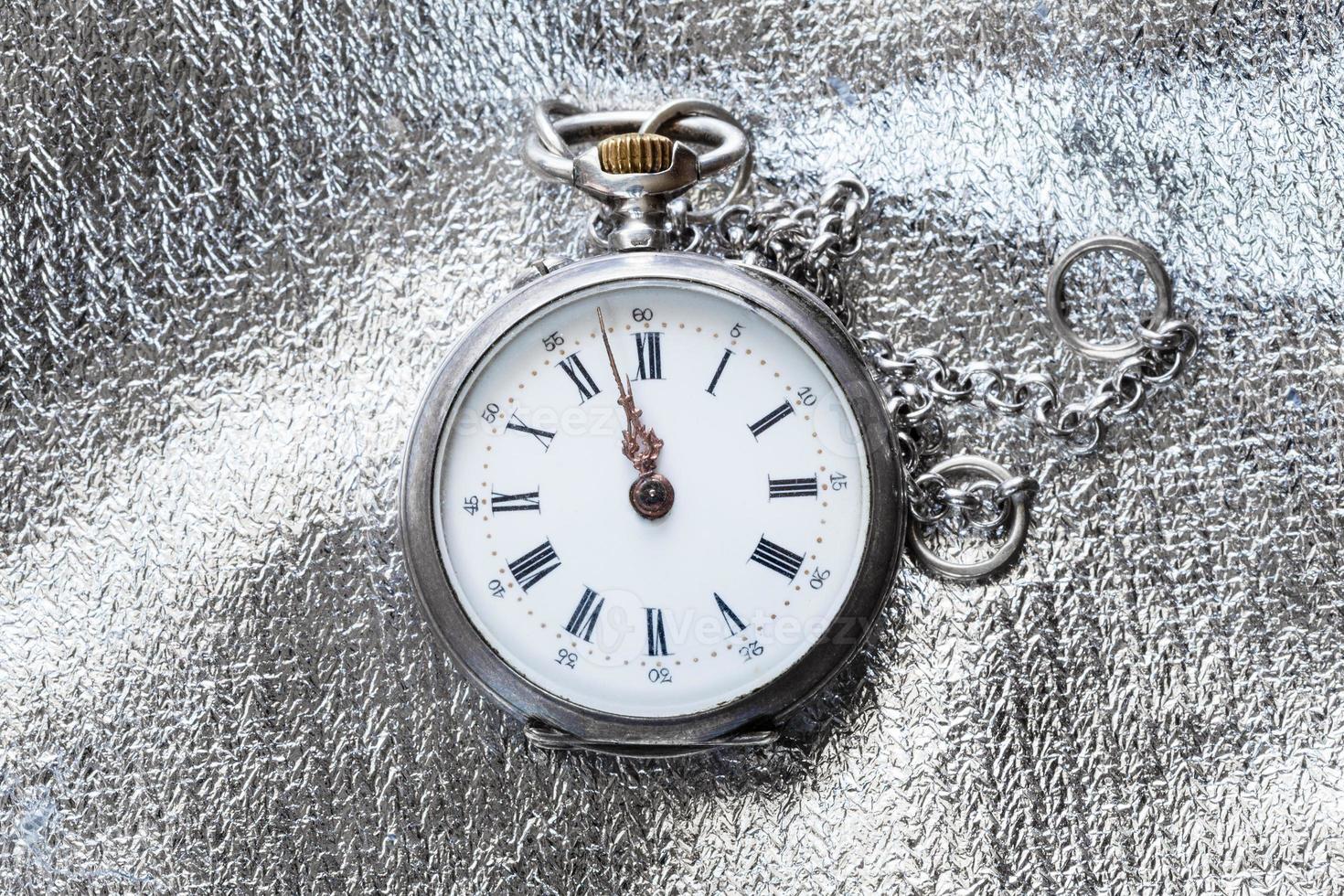 old pocket watch on silver fabric background photo
