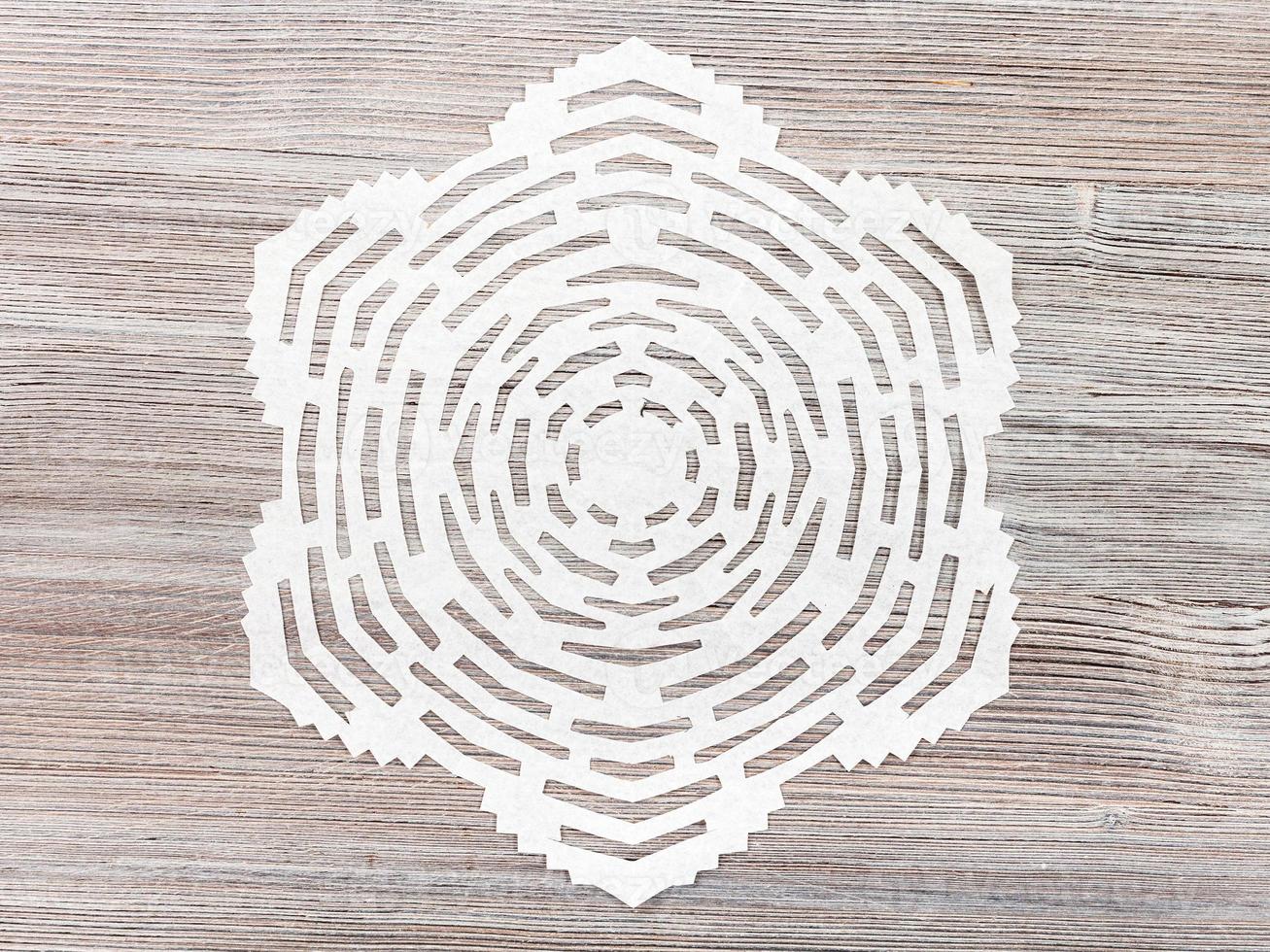 snowflake cut out of paper on light brown table photo