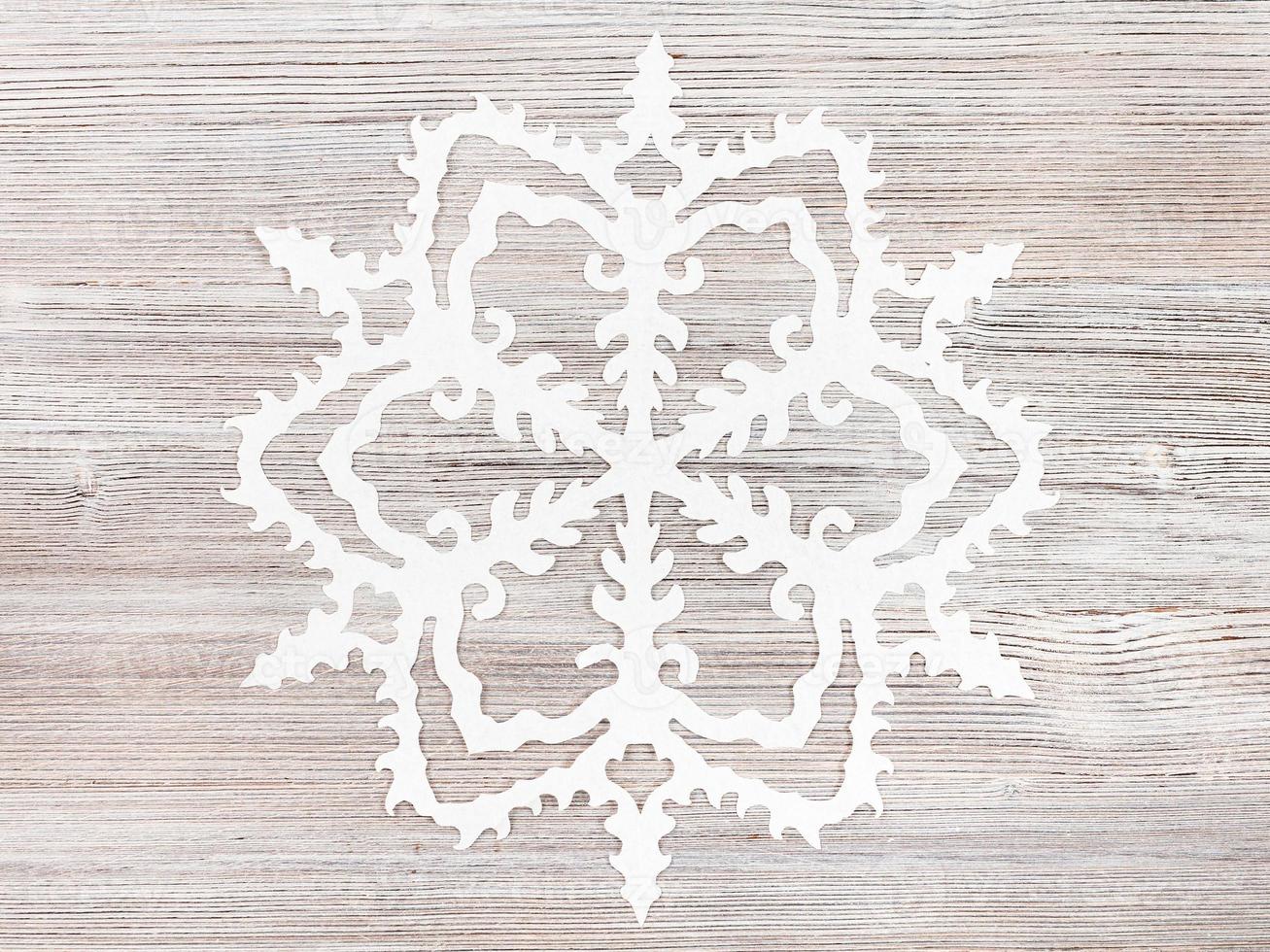 snowflake cut out of paper on light brown surface photo