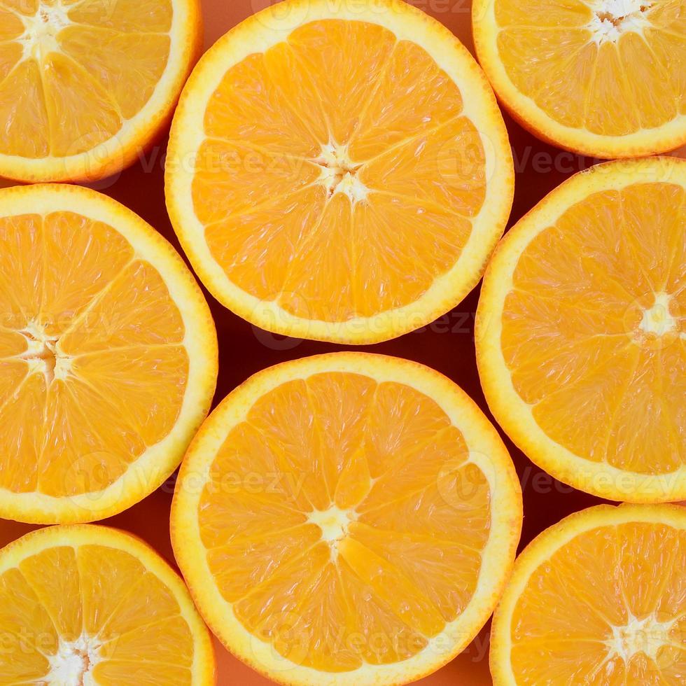 Top view of a several orange fruit slices on bright background in orange color. A saturated citrus texture image photo