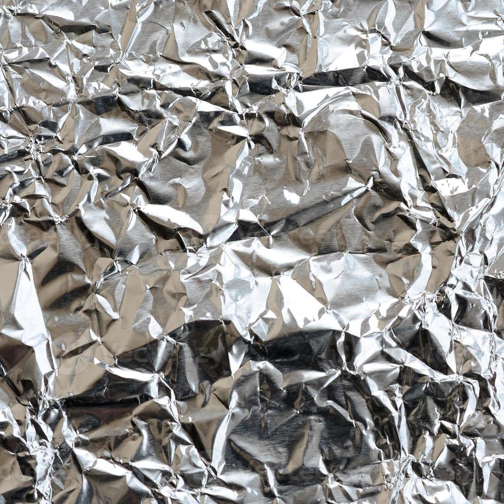 Thin wrinkled sheet of crushed tin aluminum silver foil background with