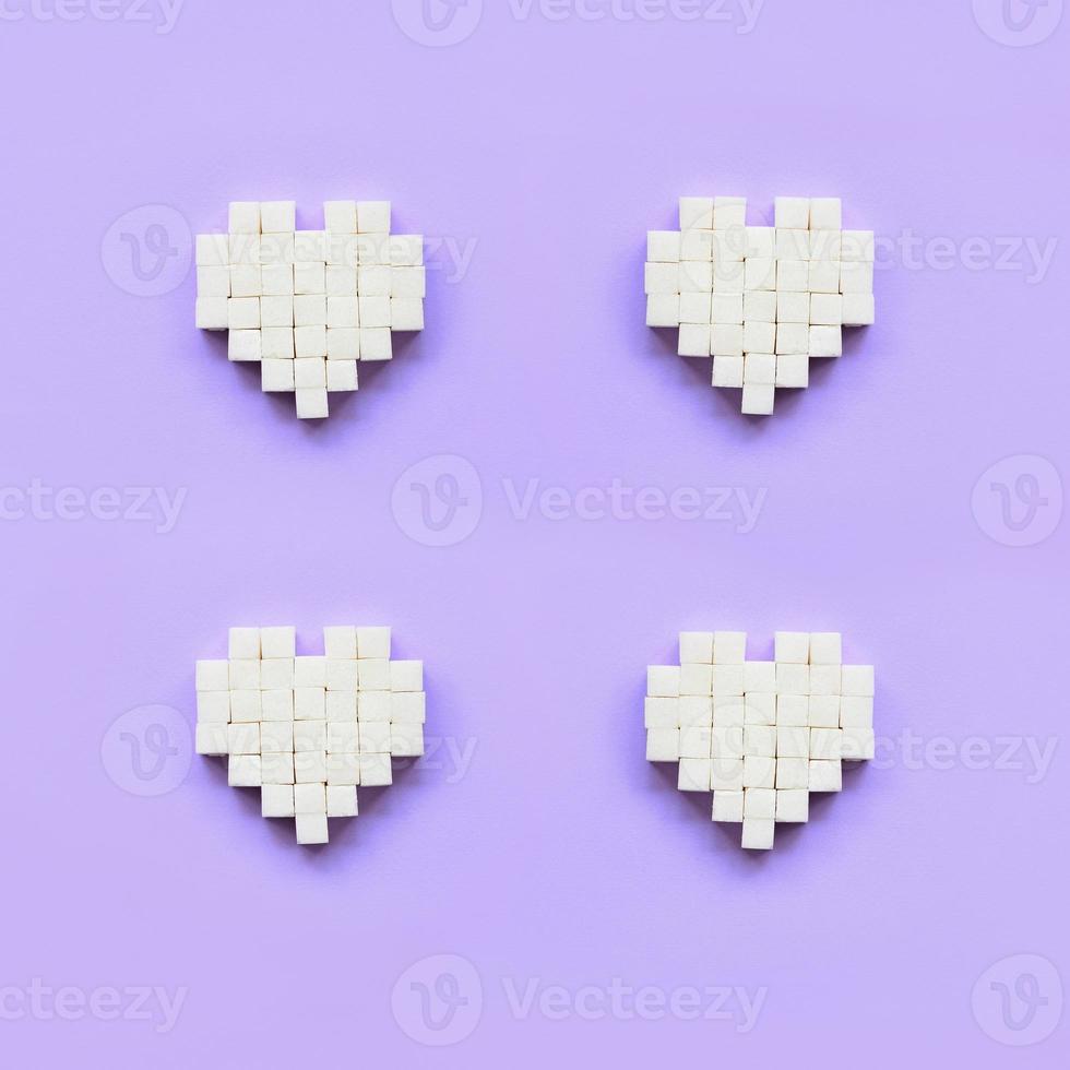 A few hearts made of sugar cubes lies on a trendy pastel violet background photo