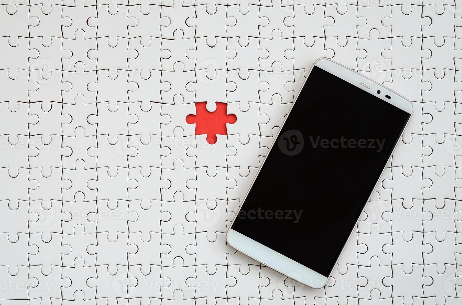 A modern big smartphone with a touch screen lies on a white puzzle puzzle in an assembled state photo