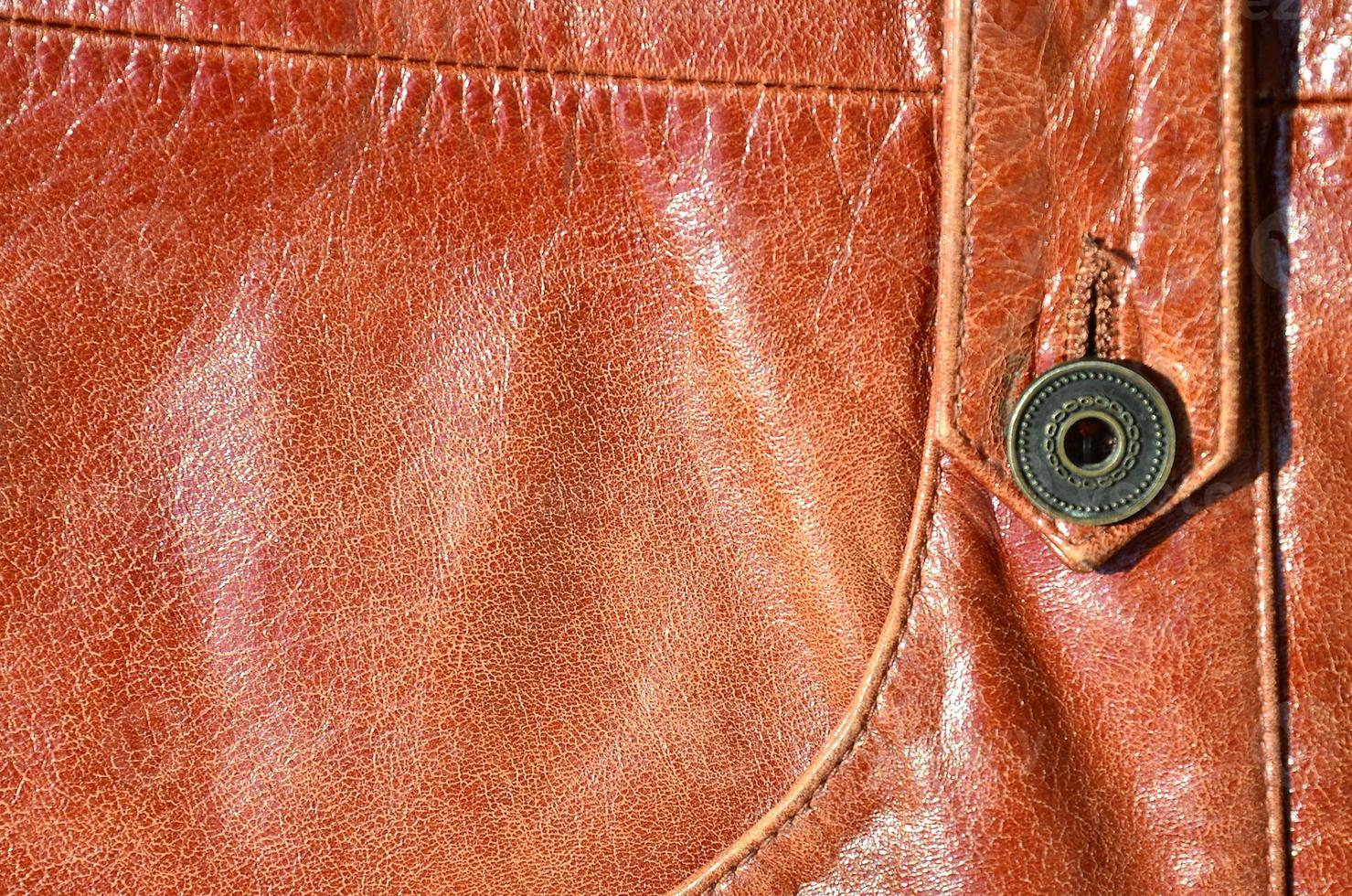 Brown leather texture. Useful as background for any design work. Macro photo of a button on outer clothing made of genuine leather