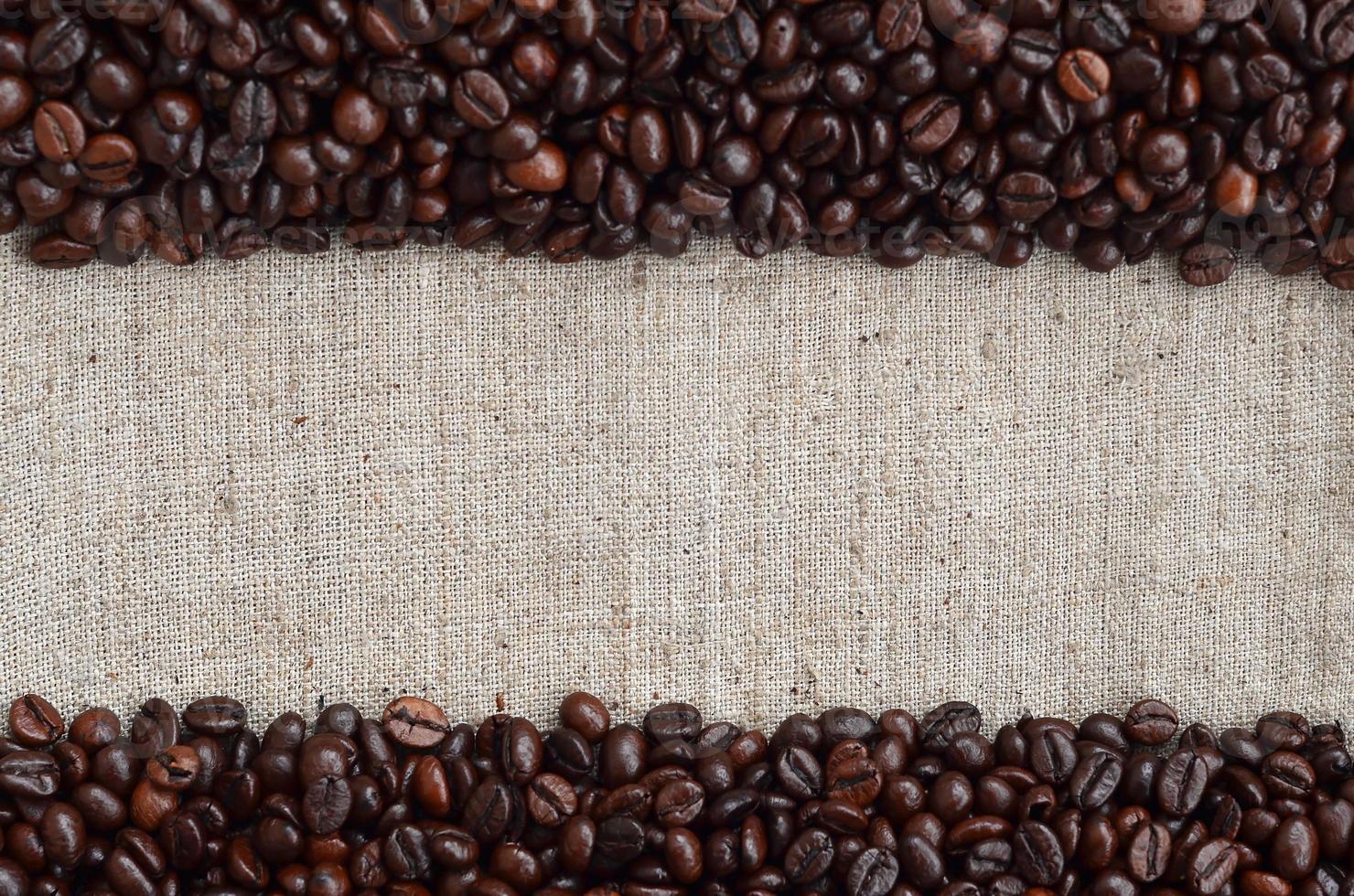 Texture of a gray canvas made of old and coarse burlap with coffee beans on it photo