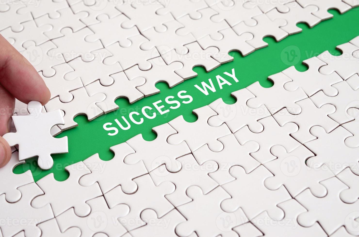 The human hand paves the way to the surface of the jigsaw puzzle, forming a green space with inscription. Success way photo